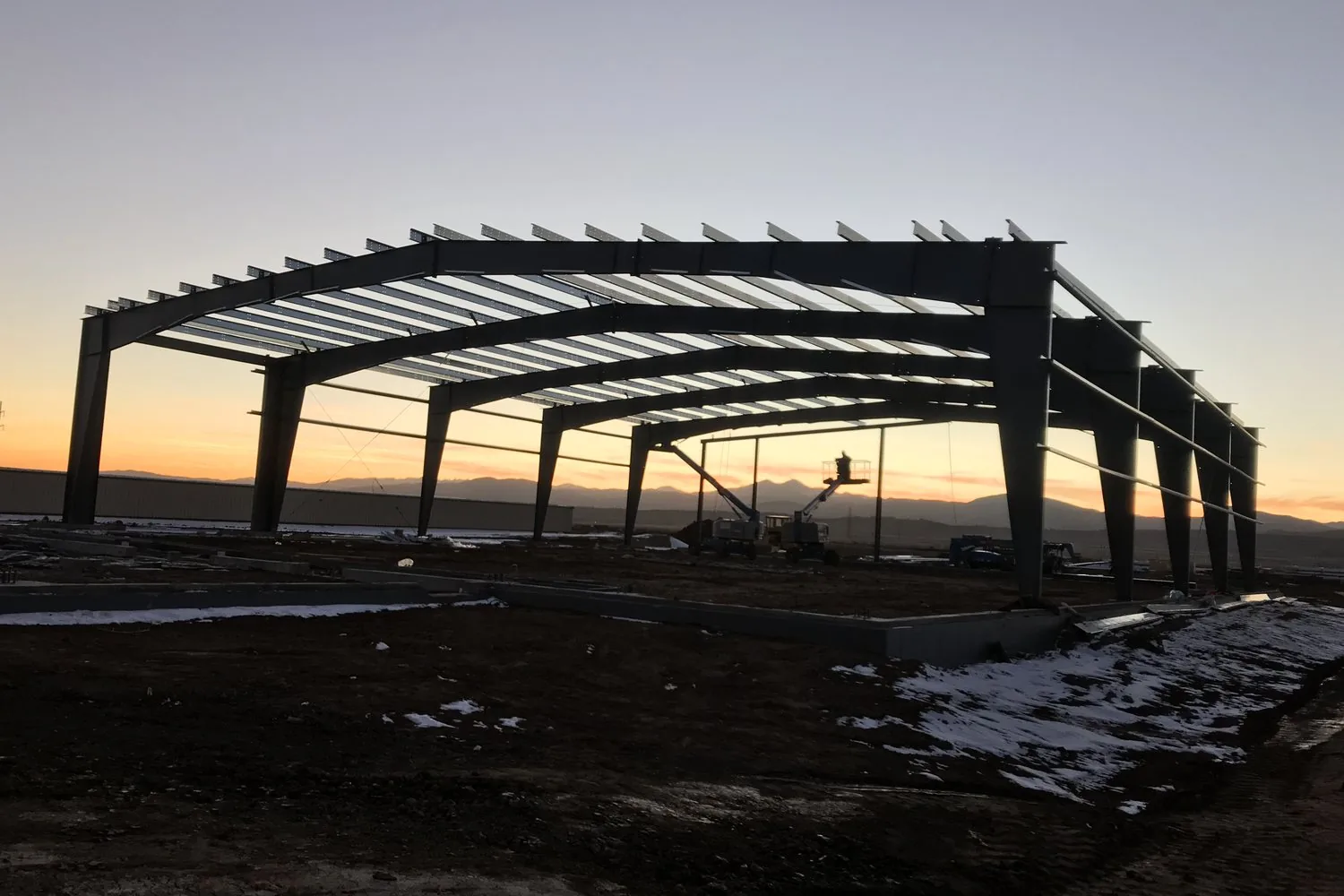 Steel building frame going up on a Rudkin commercial site at sunset