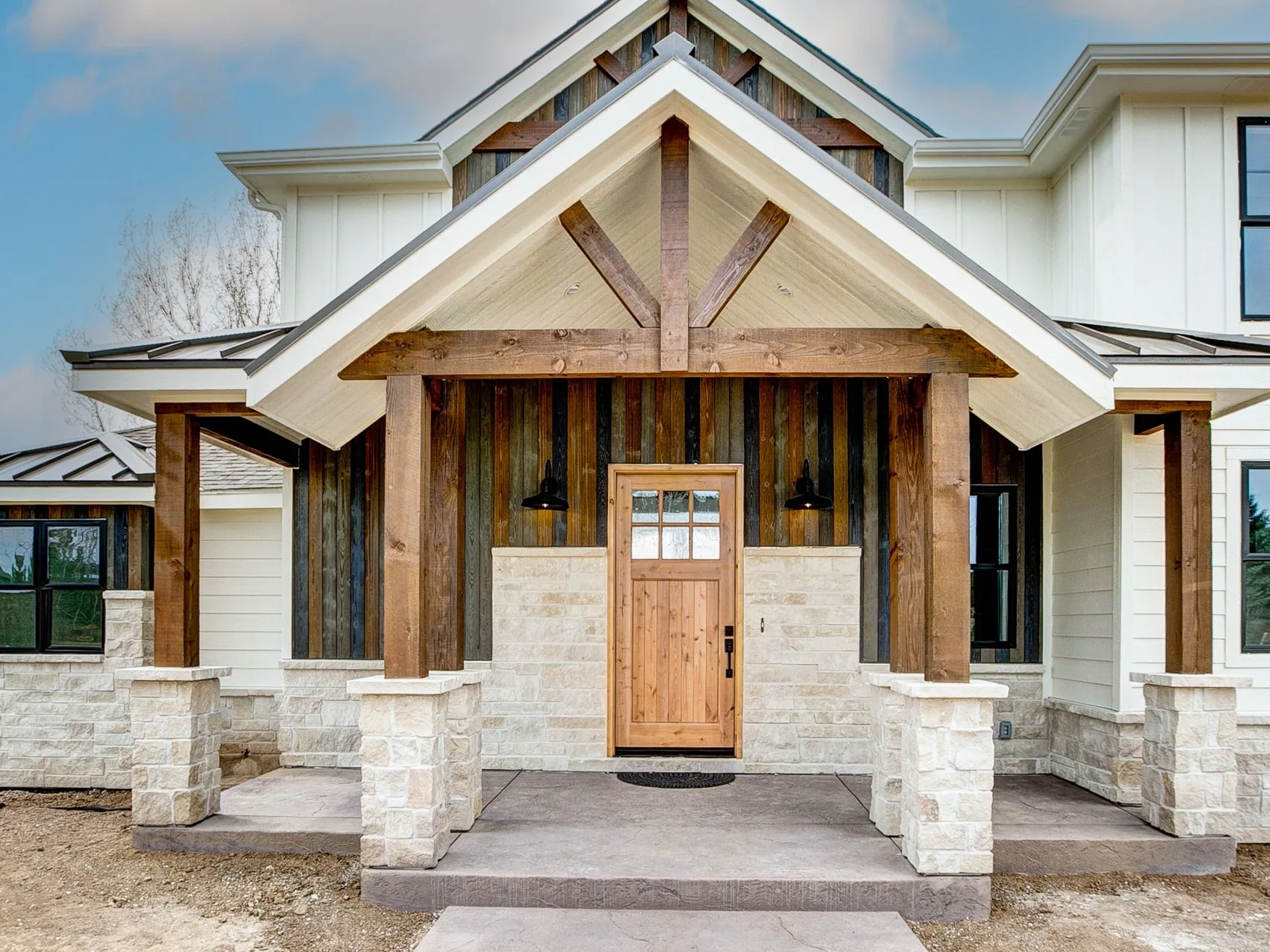 Front entry of a custom home built by Rudkin with timber posts and stone
