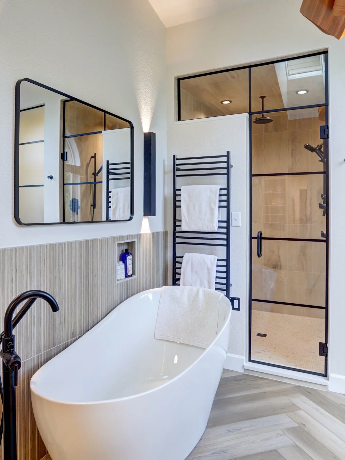 Primary bathroom with a freestanding tub and a black framed glass shower