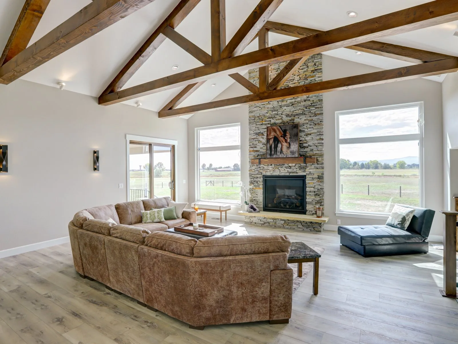 Great room with exposed timber trusses and a stone fireplace
